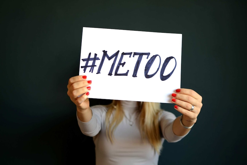 A woman holds a sign with the words #MeToo.