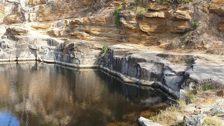 A waterhole surrounded by rocky cliffs.