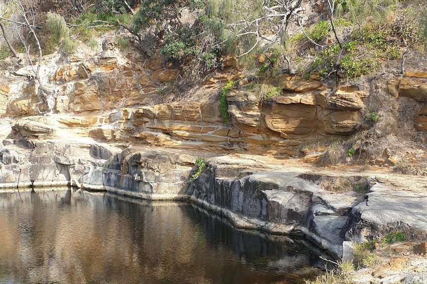 A waterhole surrounded by rocky cliffs.