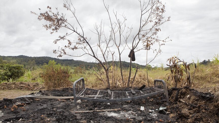 The scorched remains of a house set alight during an attack on a family accused of sorcery. Only a bedframe remains.