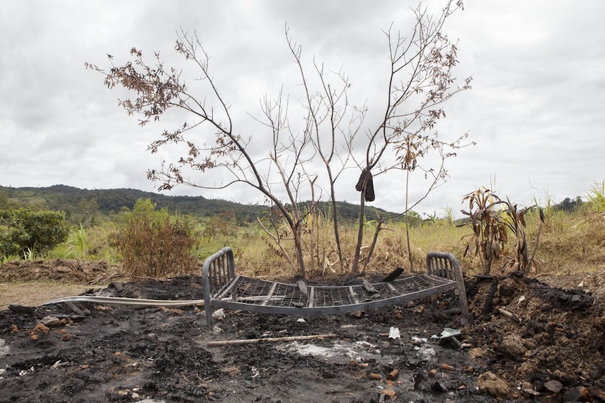 The scorched remains of a house set alight during an attack on a family accused of sorcery. Only a bedframe remains.