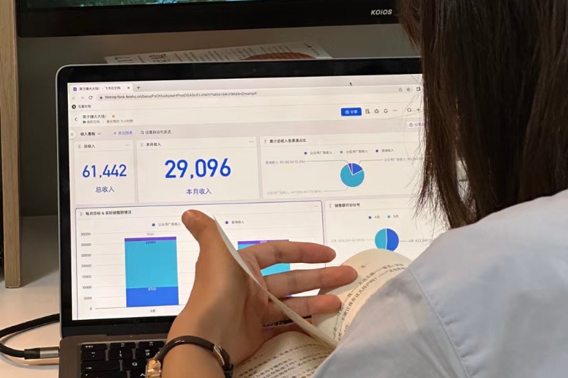 A woman sits at a computer and looks at a bar chart