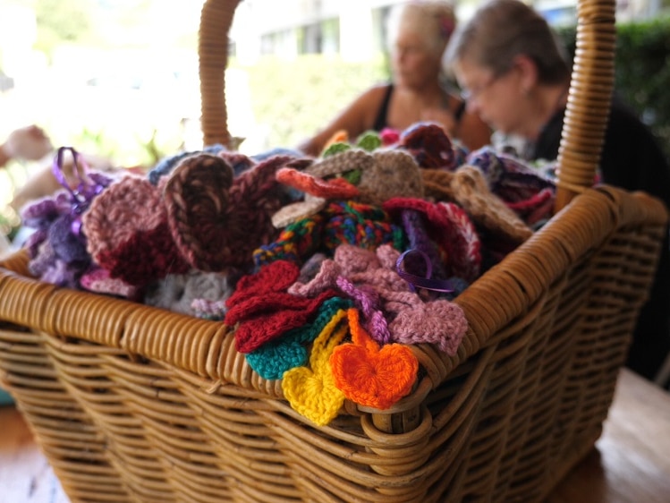 A basket full of tiny crocheted hearts sits on a table at a cafe.