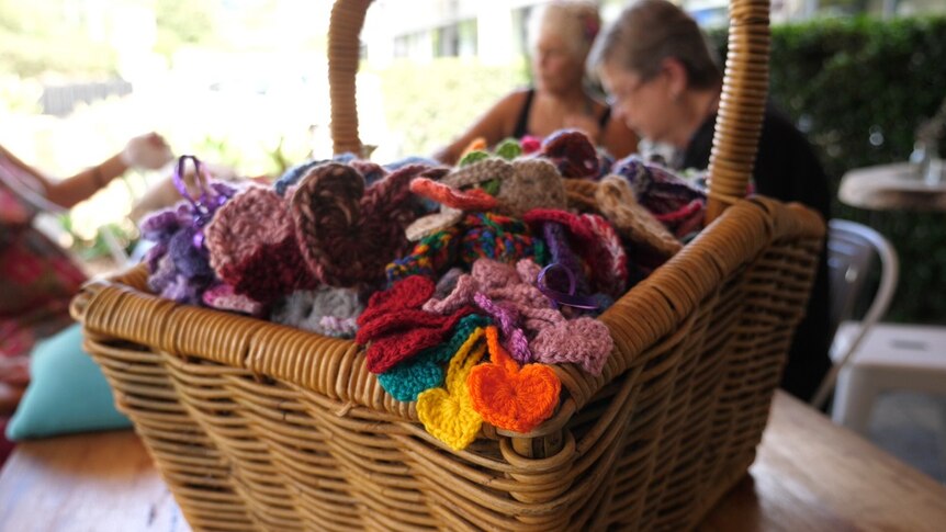 A basket full of tiny crocheted hearts sits on a table at a cafe.