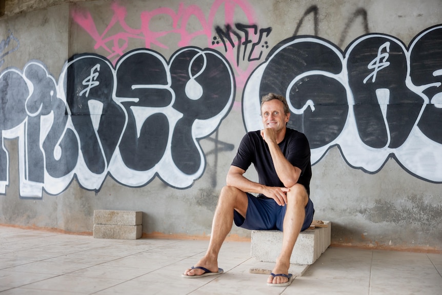 Man sitting in front of graffiti