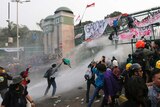 Student protesters are sprayed with a water cannon during a protest outside parliament in Jakarta