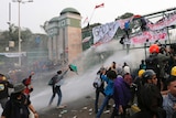 Student protesters are sprayed with a water cannon during a protest outside parliament in Jakarta
