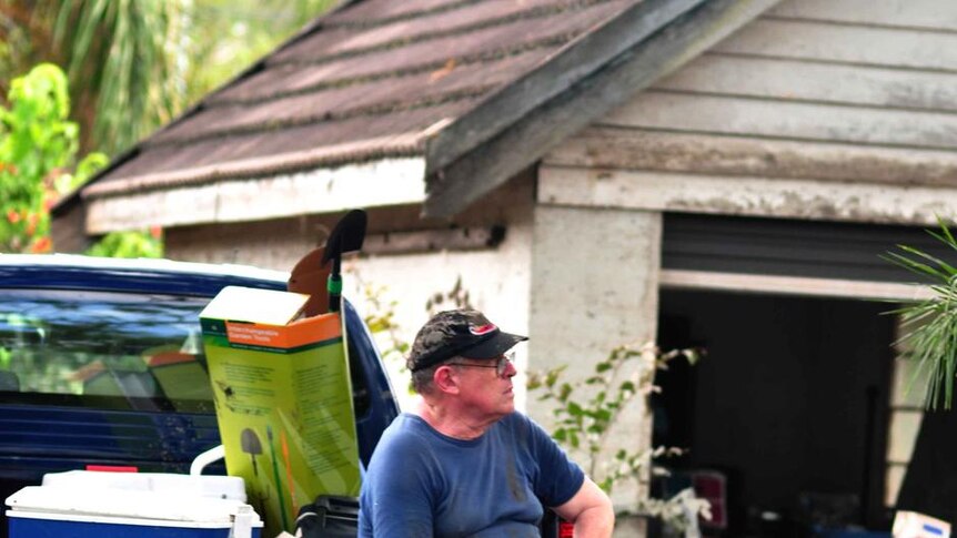 A man rests on the back of a truck while helping with the flood clean-up