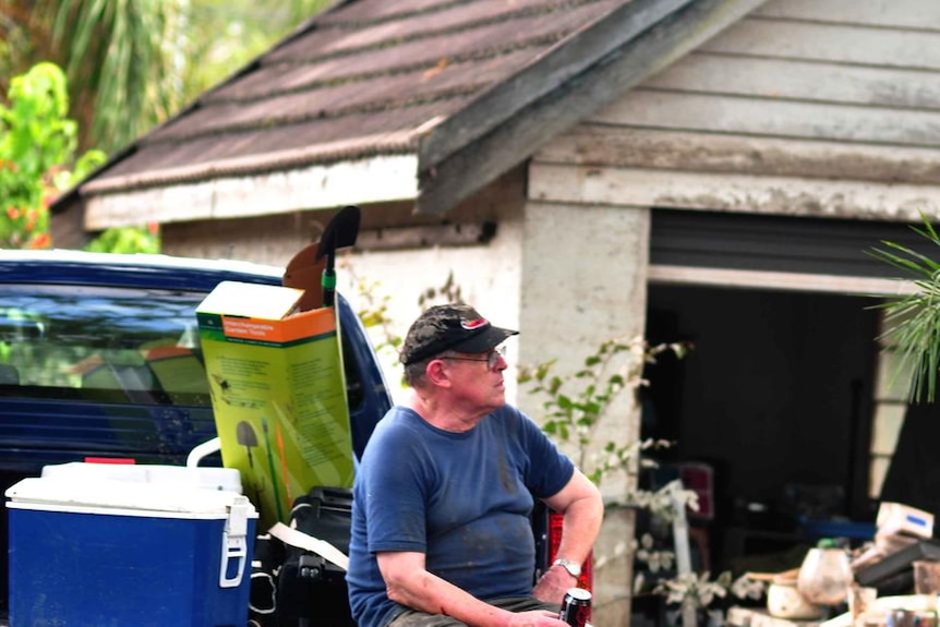 A man rests on the back of a truck while helping with the flood clean-up in Fairfield in Brisbane on January 15, 2011.