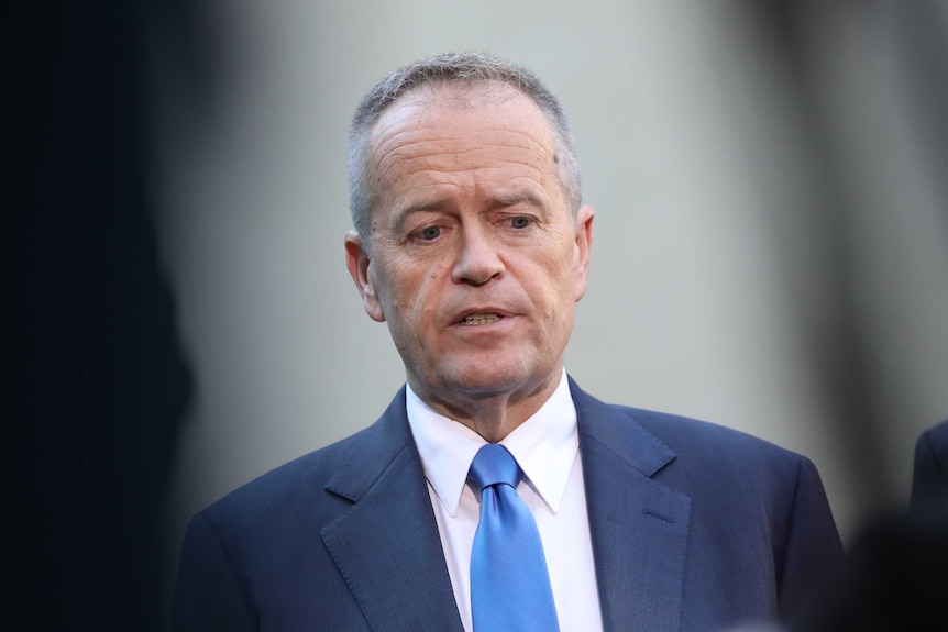 Mr Shorten looks down while mid sentence. He's wearing a blue tie and suit.