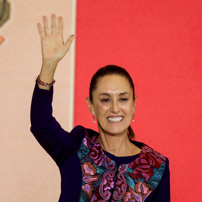 A woman smiling waving her hand in the air. 