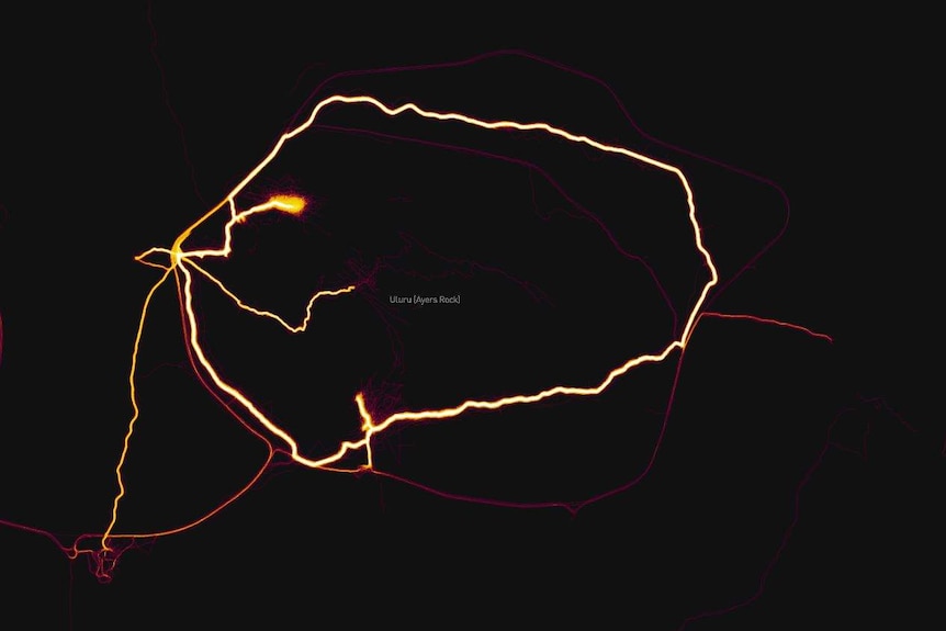 A path around Uluru is illuminated against a black backdrop.