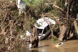 A car is trapped in a tree at Dungog highlighting the devastation of the NSW storm