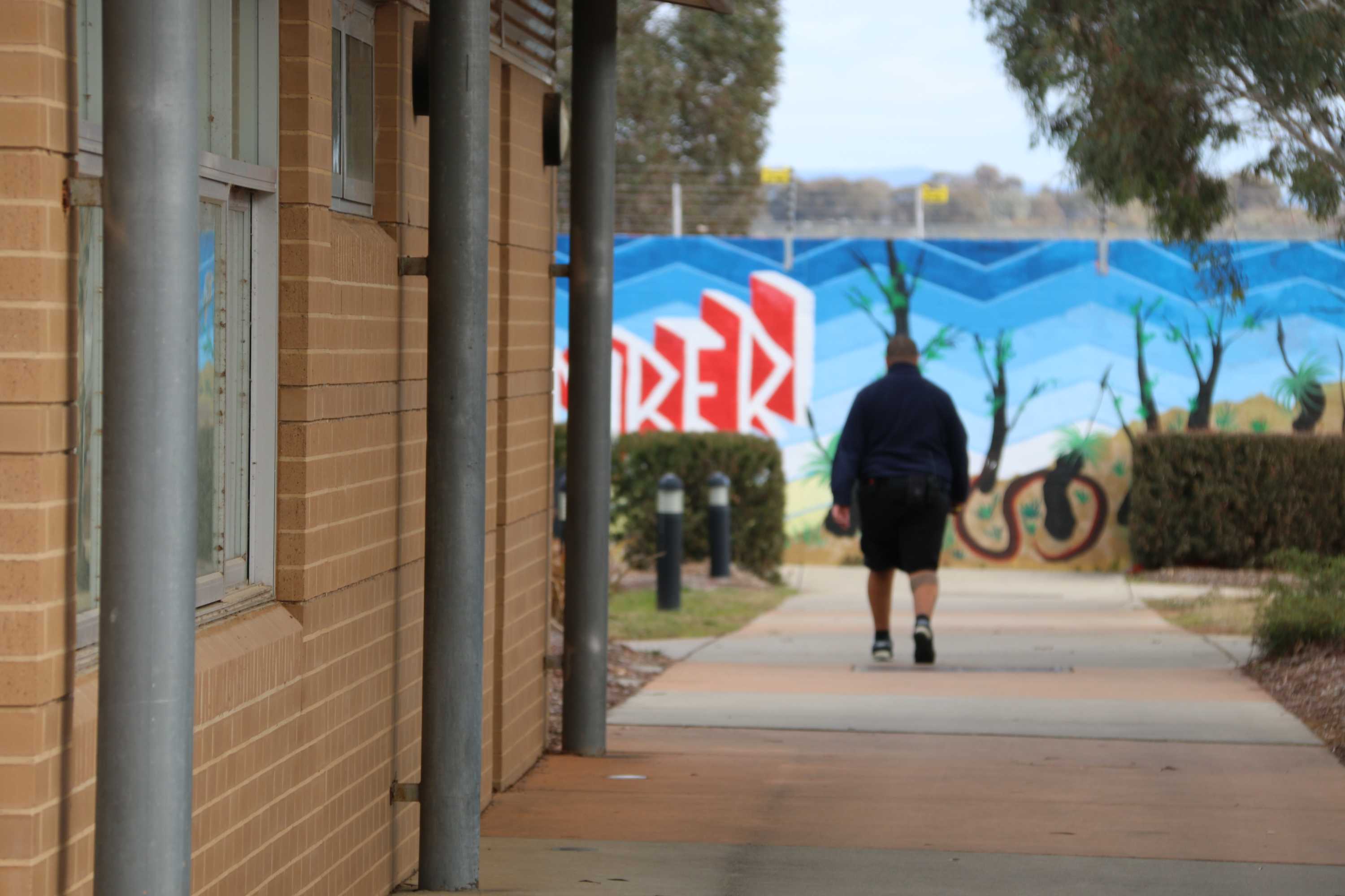 Shot of outside a building, with a person walking off out of focus in front of a painted wall.