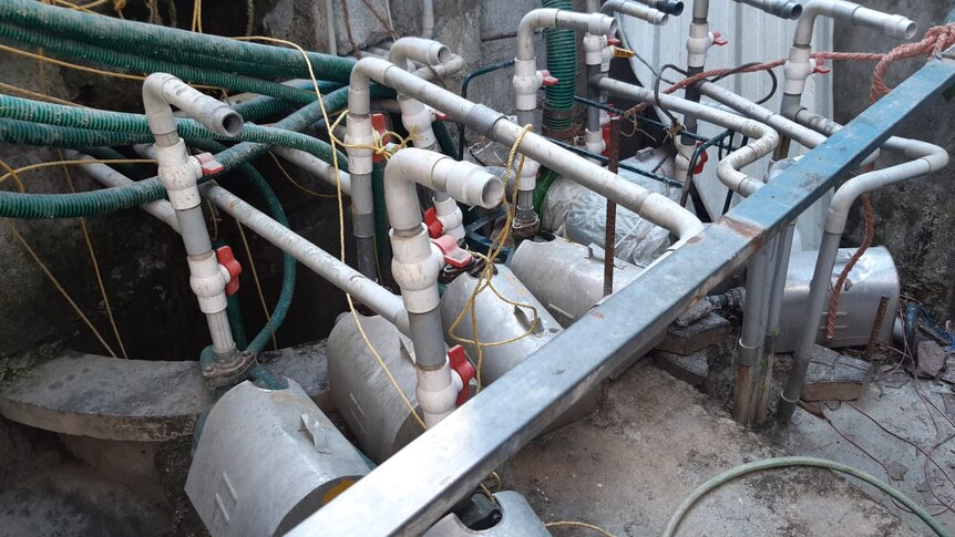Pumps and pipes sit near a concrete wall.