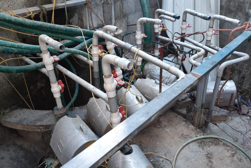 Pumps and pipes sit near a concrete wall.