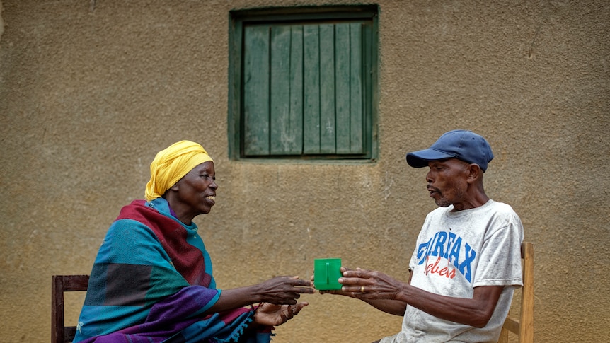 Genocide survivor Laurencia Mukalemera, left, a Tutsi, is offered a cup of water by Tasian Nkundiye, a Hutu