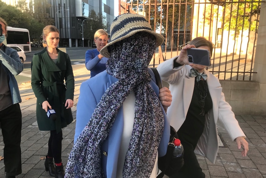 A woman leaves court with her face covered.