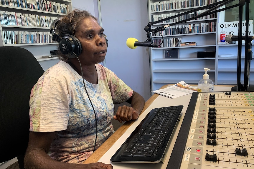 An Aboriginal woman wearing headphones speaks into a radio mic.