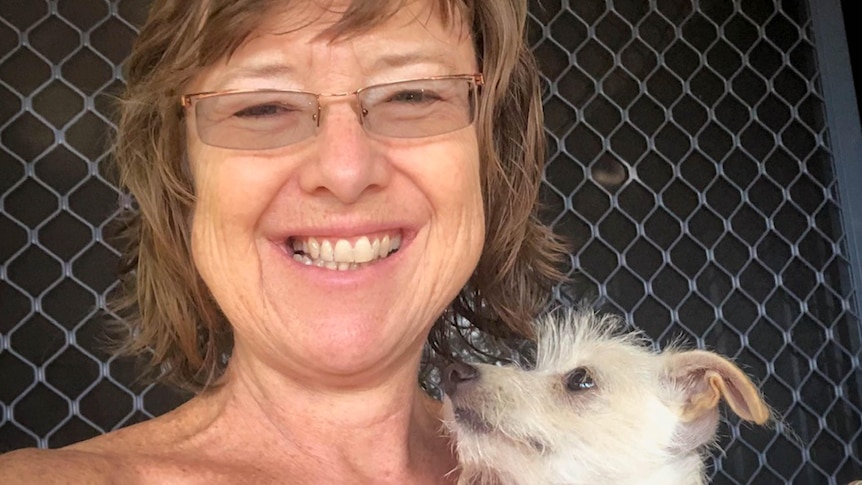 A woman smiles while holding a small dog