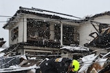 Rescue worker slips in snow in Japan quake rubble