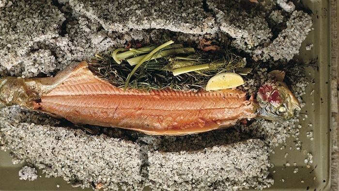 A baked fish resting on a bed of rock salt.