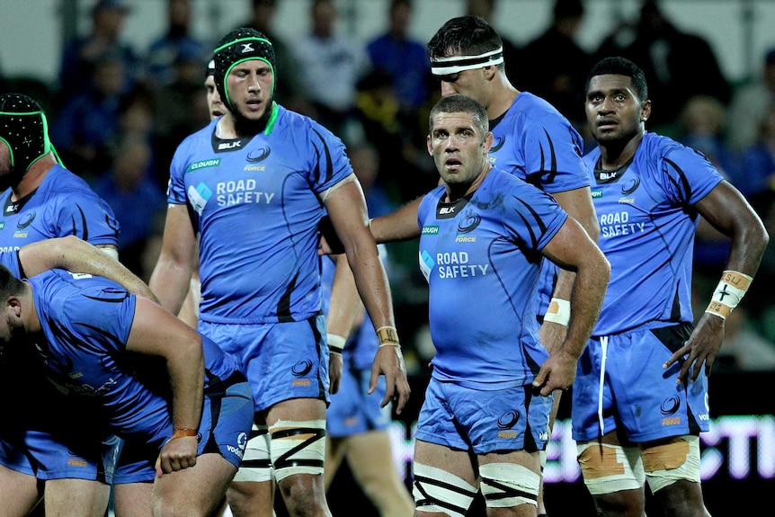 Six Western Force players including Matt hodgson prepare for a scrum wearing blue jerseys and shorts in a Super Rugby match.