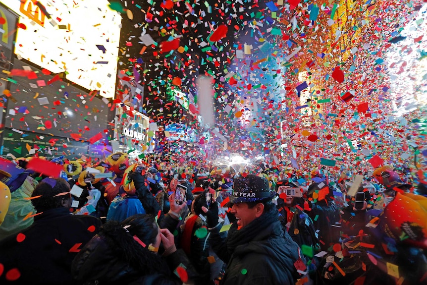 Brightly coloured confetti falls on a packed crowd in Time Square