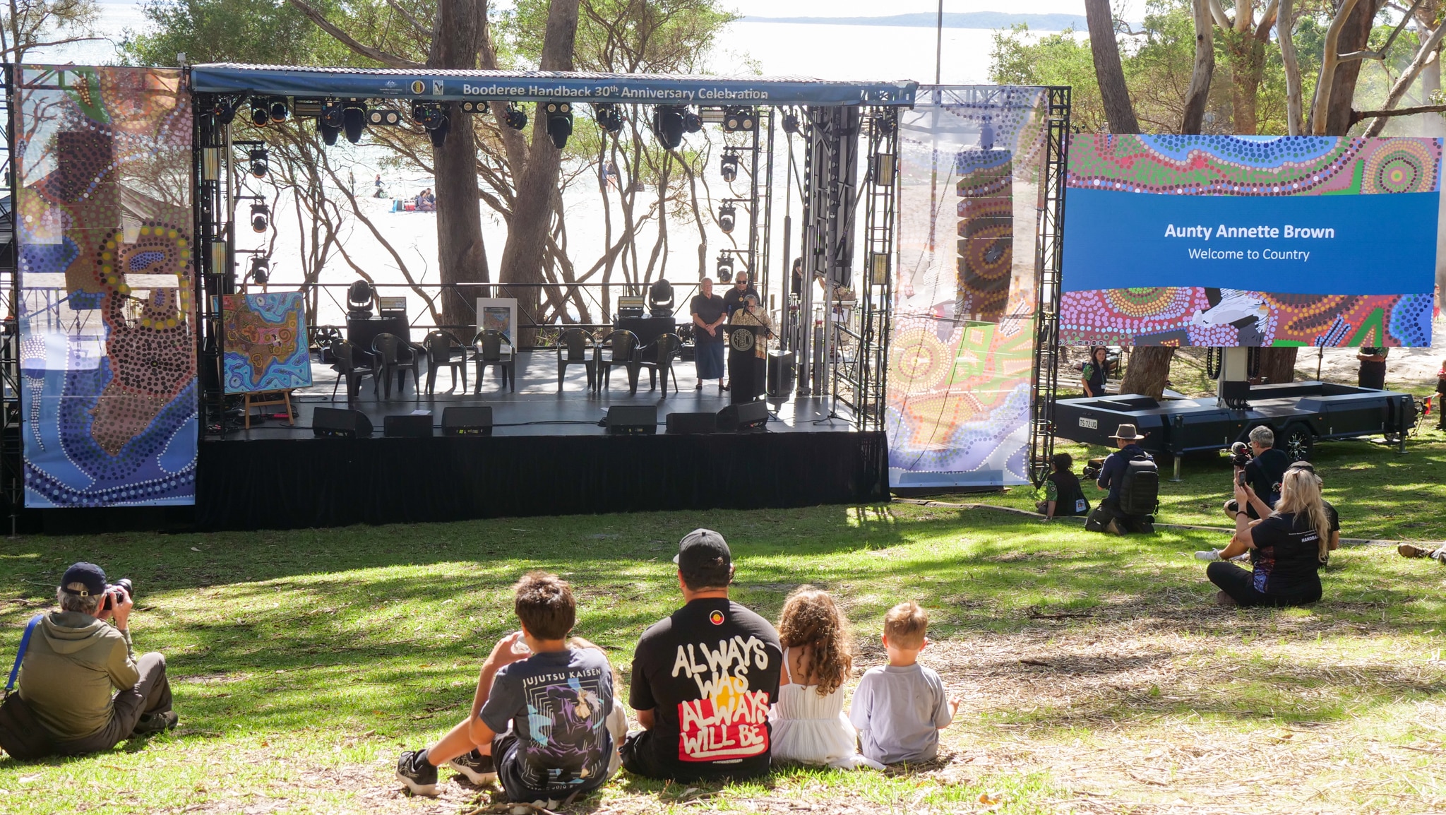 Сцена установлена ​​на траве в национальном парке, граничащем с пляжем. 