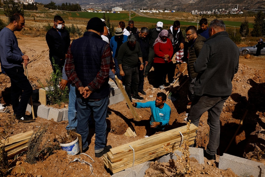 People near a grave at a cemetary. 