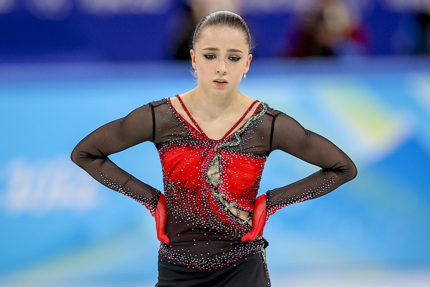 A figure skater puts her hands on her hips and looks disappointed