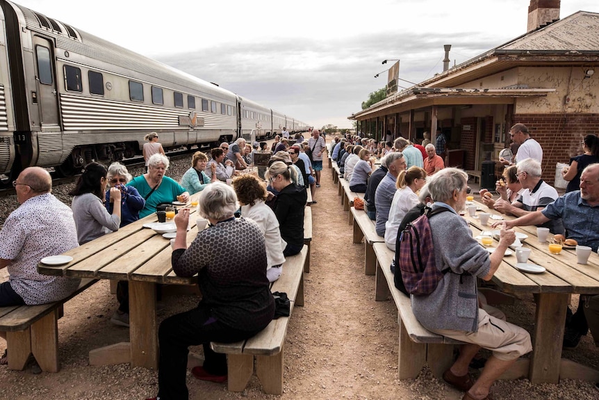 A large group of people eating breakfast at wooden tables