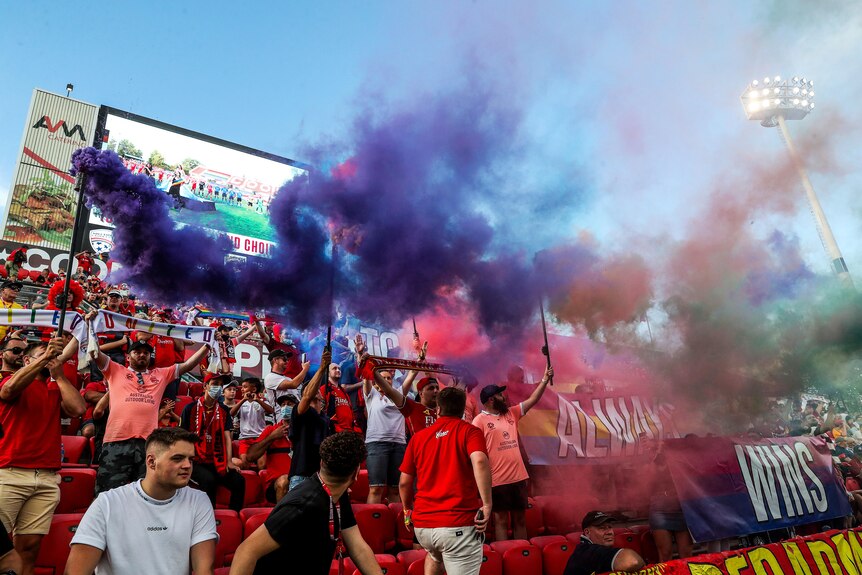 Soccer fans hold up signs and smoke flares during a match
