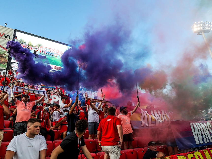 Soccer fans hold up signs and smoke flares during a match