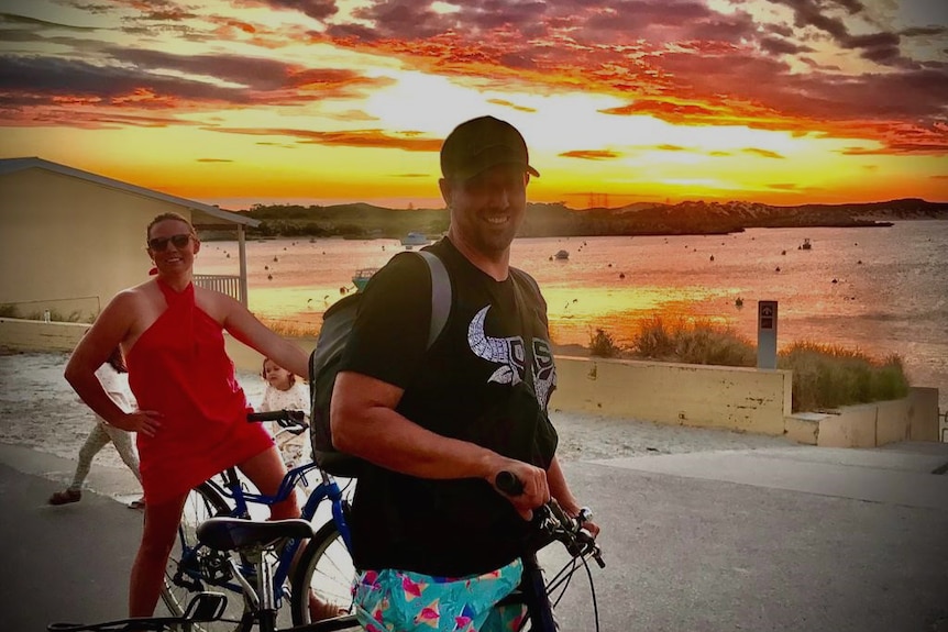 A woman and amn on bikes in front of a brillaint Rottnest sunset.