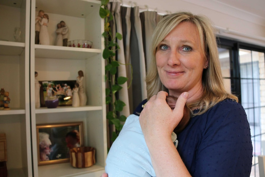 Woman holding a newborn baby inside a home