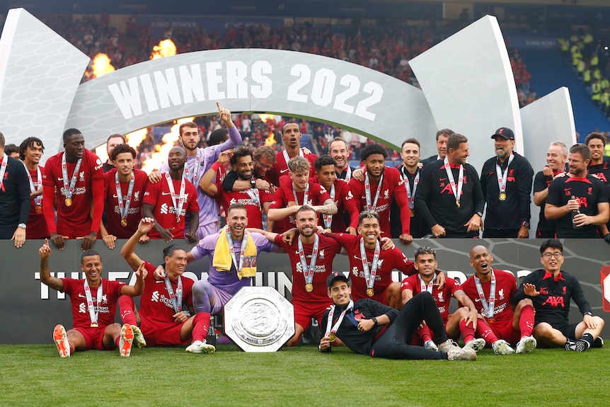 A male soccer team wearing red wins a trophy