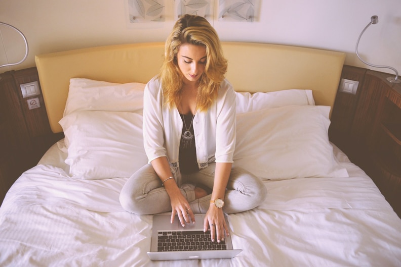 A woman uses her laptop computer on her bed.