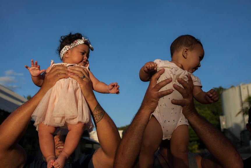 Christmas Island babies held aloft by their dads.