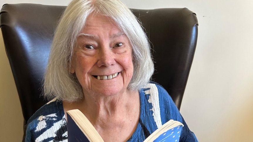 Marion Halligan reads a book in a chair