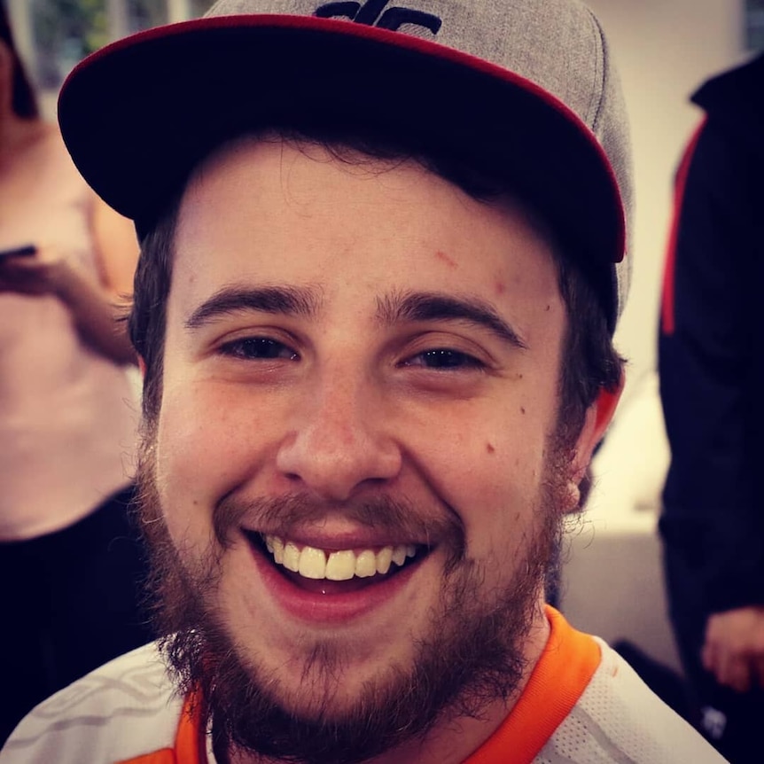 A young man with a beard in a flat-brimmed cap