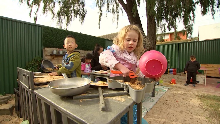 A boy and a girl use a mud kitchen