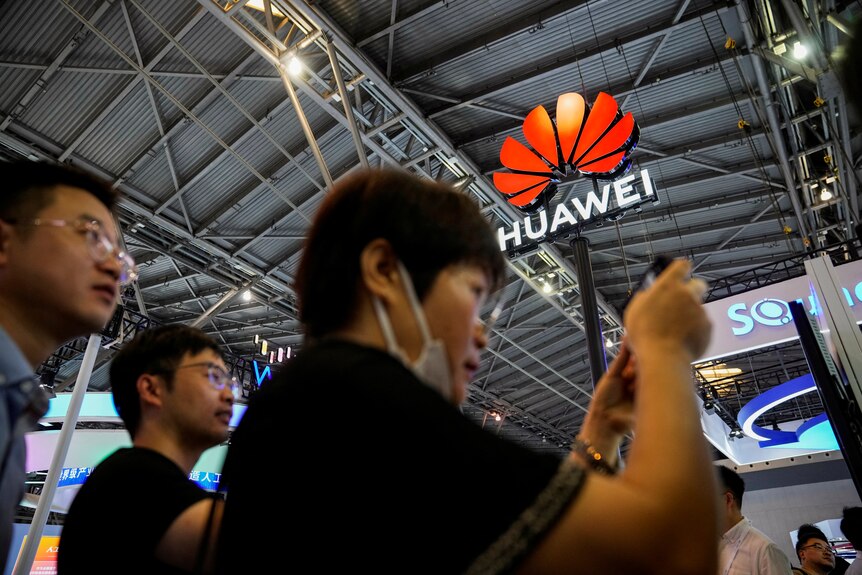 Un homme prend un téléphone sur un téléphone avec un signe Huawei en arrière-plan. 