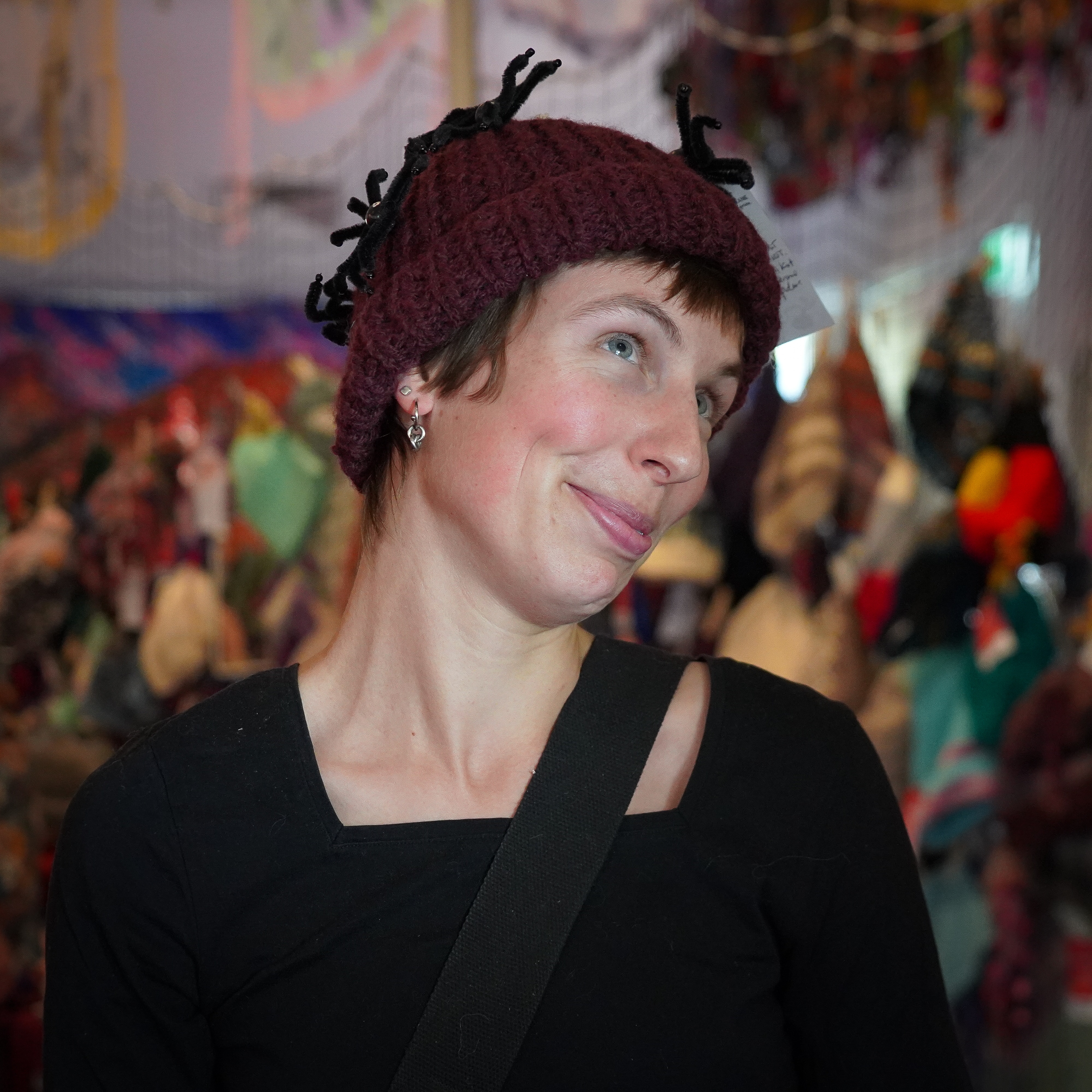 A woman posing for the camera while wearing a handmade maroon beanie.