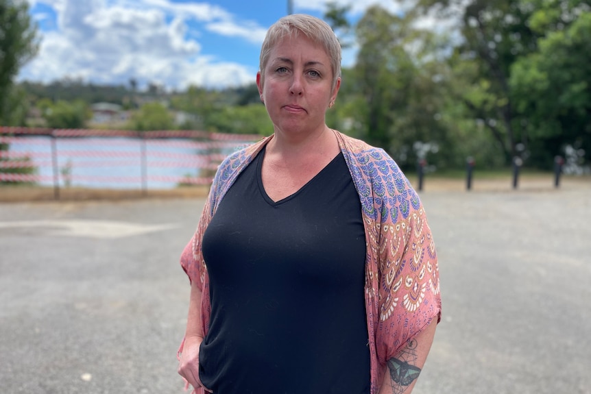 A woman with short blonde hair stands in front of a river