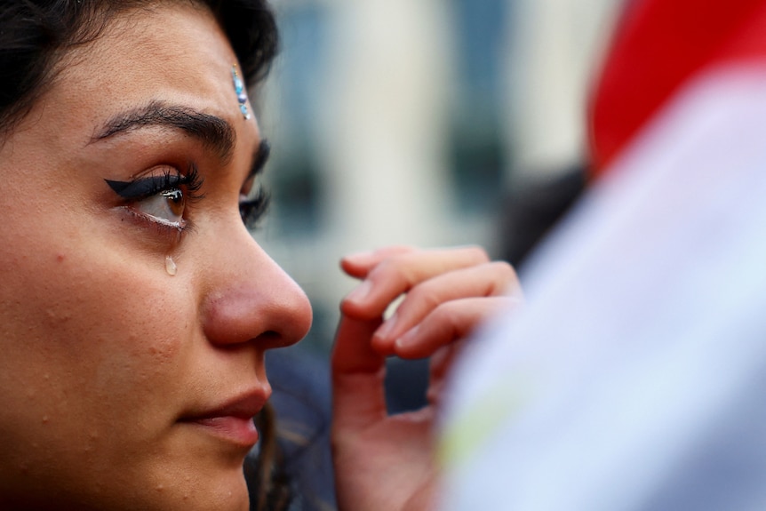 A woman's face in profile as a tear runs down her cheek 