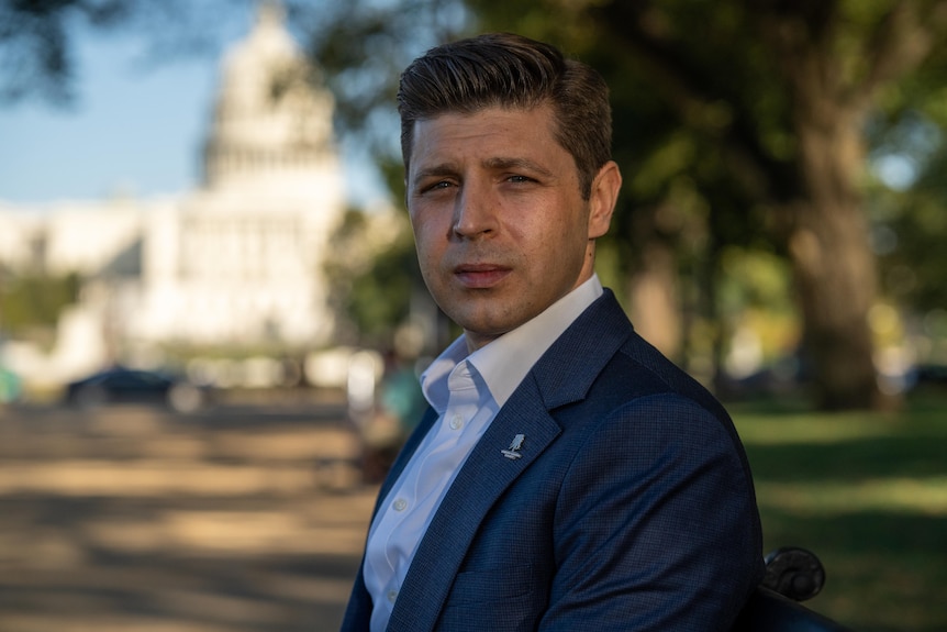 Man wearing a suit, sitting outside.