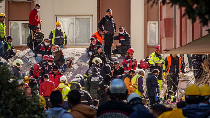 A group of people stand among rubble