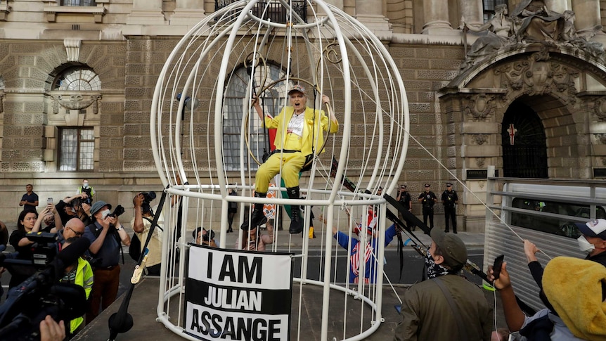 Fashion designer Vivienne Westwood sits suspended in a giant bird cage in protest