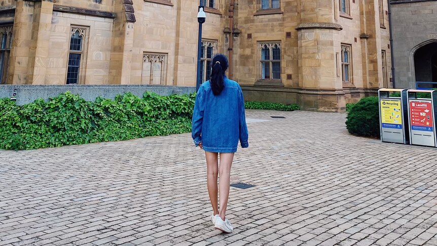 A photo of drishti from the back standing in front of her university building in Melbourne.